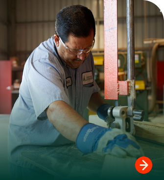 Employee cutting plywood to size on a band saw