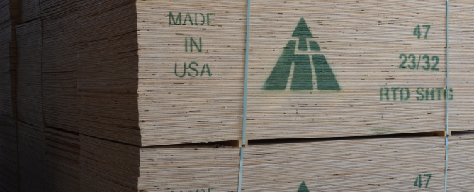 Large stack of industrial plywood stamped with brand and Made in USA in green paint.